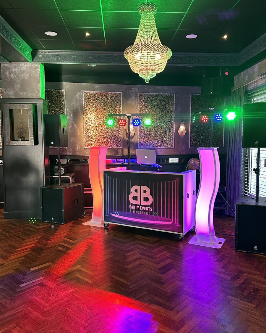DJ-booth met groene kroonluchter en rood-paarse lichtshow
